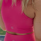 Photo is the back side of blonde haired women from the waist to the head.  This is to show off the back side of a long lined tank top that she is wearing.  She also has matching biker shorts on as well.  Both items of clothing are in the color bright pink.