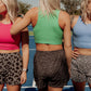 3 blonde women standing in the middle of a tennis court wearing long lined tank tops and printed running shorts