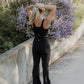 White women with blonde hair wearing a black tank top and flare leggings standing with her back facing the camera.  She is putting up her hair into a pony tail