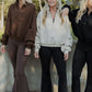 3 white women with all blonde hair standing infront of a concrete wall.  they are all looking in the opposite directions.  They are all wearing the same sweater but in three different colors. 