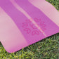 picture of a pink yoga mat that is laying on green grass.  