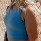 Blonde curly haired women up close on a bright blue tank top that she is wearing.  This photo is to show off the tank top and its features.