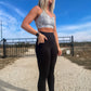 blonde haired white women standing on a dirt road showing off the pockets on her black leggings